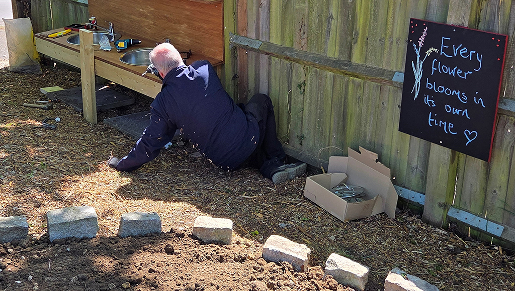 A volunteer at work, building a play area with a double sink unit.